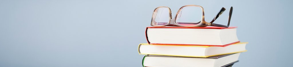 Ein Stapel Bücher auf dem eine Brille liegt