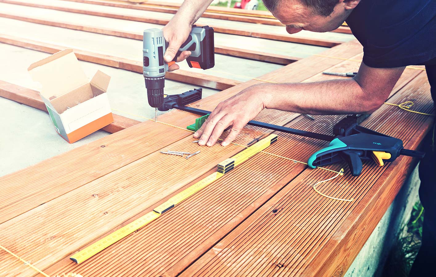 Professionelle Terrassenmontage von Holz Meeser Mann der eine Holzterrasse verlegt