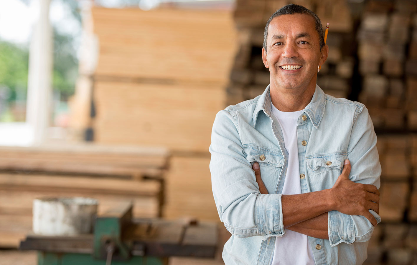 Ein Handwerker vor einer Lagerhalle mit Schnittholz