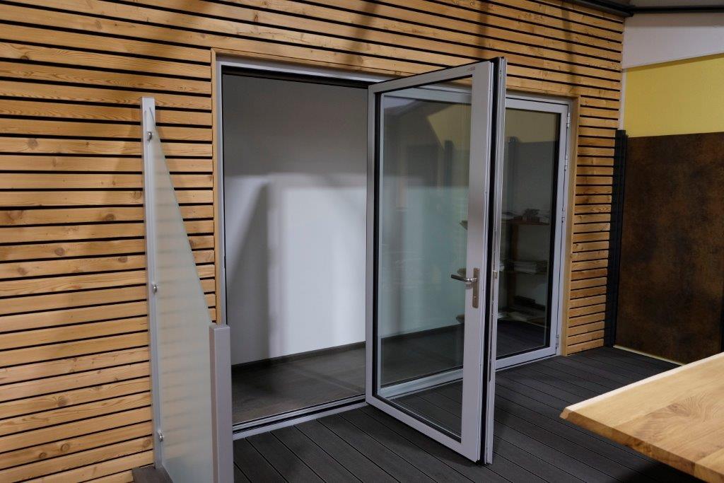 Faltwand aus Glas der Marke Solarlux an einem Haus mit Holzfassade