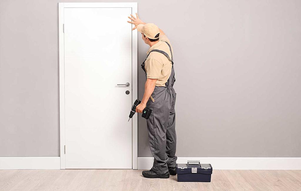 Ein Handwerker prüft eine Zimmertür